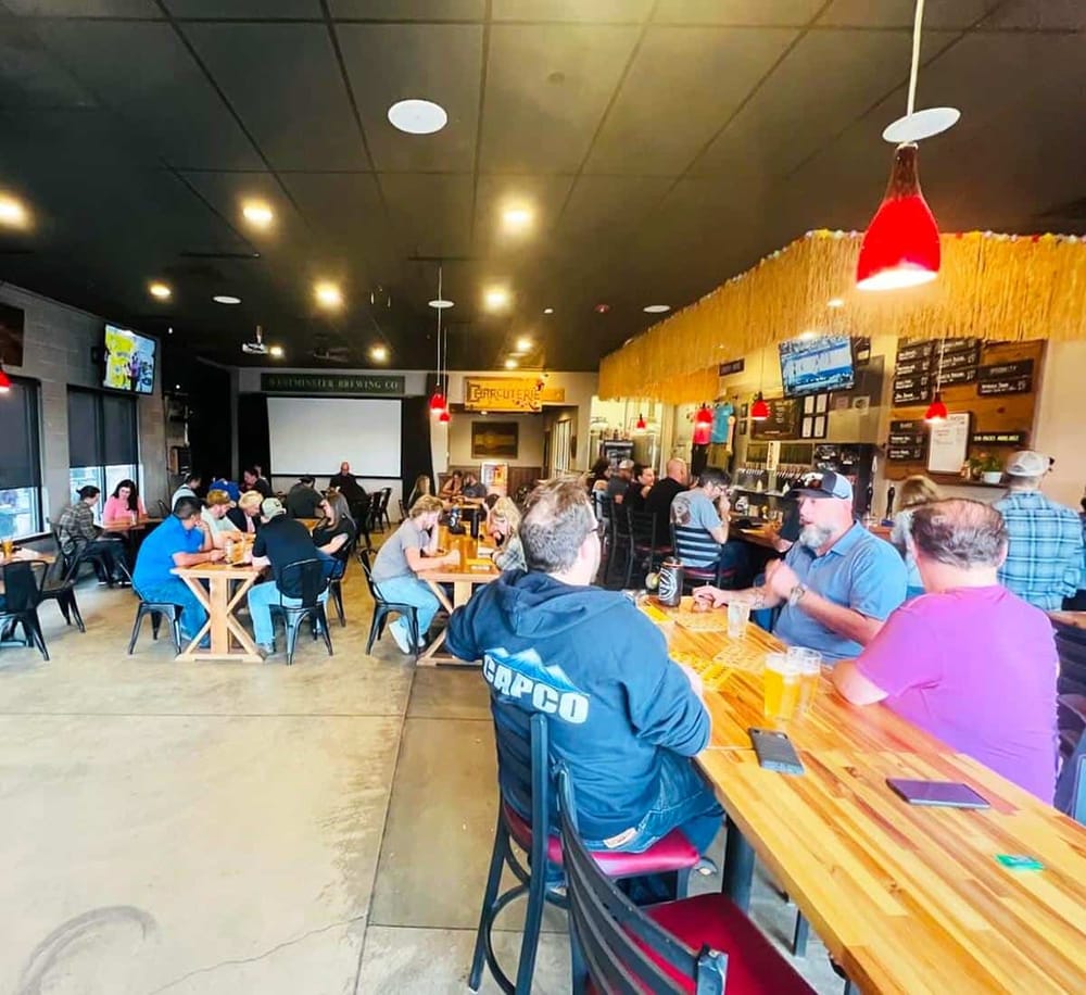 Bright, busy brewery bar with patrons enjoying drinks and socializing in a modern, lively atmosphere.