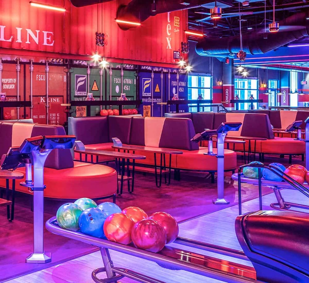 Brightly lit indoor bowling alley with stylish seating and colorful bowling balls, ideal for entertainment and fun activities.