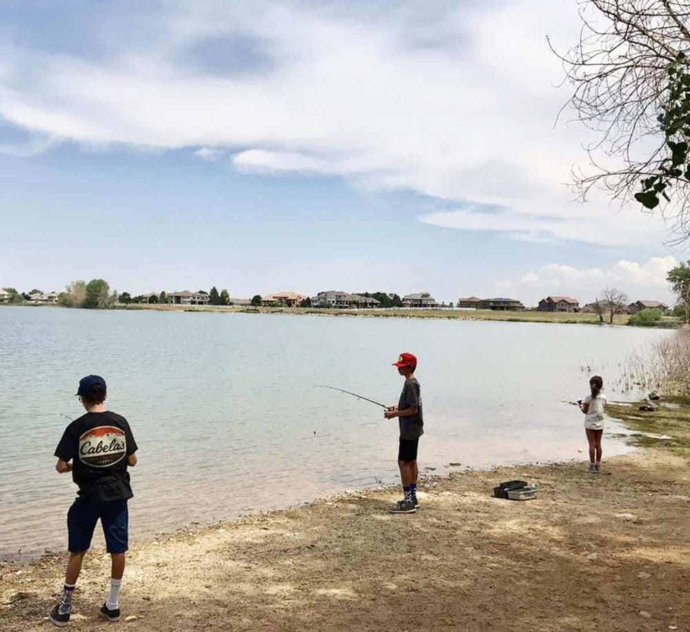 Children fishing at a tranquil lake fishing spot, perfect for family outdoor adventures and relaxing weekend outings.