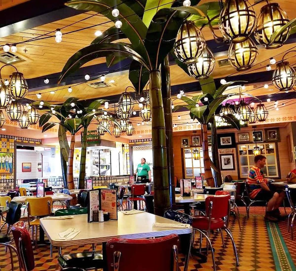 Lush indoor restaurant with tropical decor, bamboo-themed lighting, and vibrant dining atmosphere.