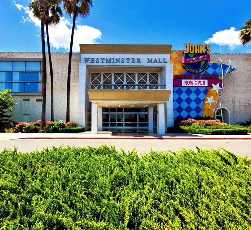Colorful shopping mall entrance with palm trees and vibrant signage at Westminster Mall, Orlando, FL.