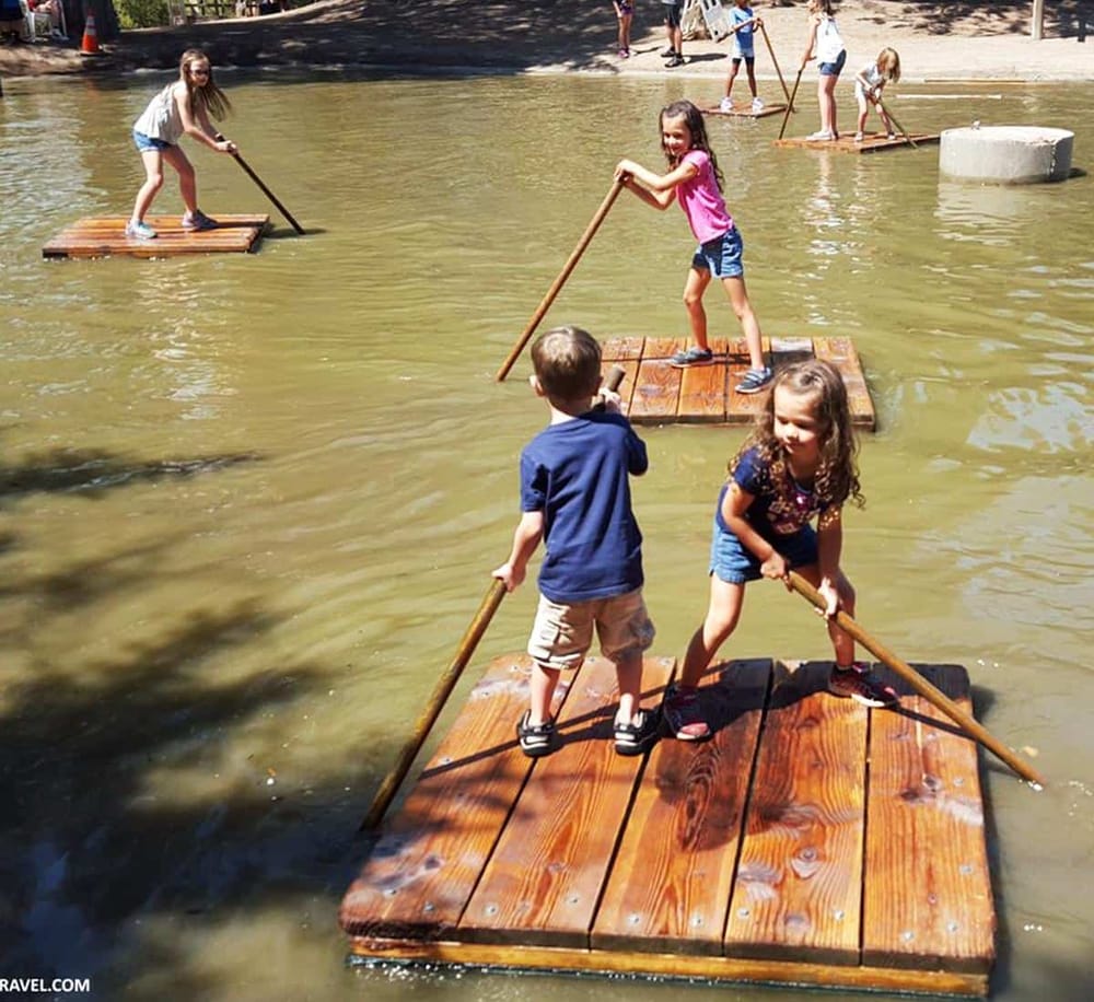 Children paddleboarding on a lake in a daytime outdoor setting.