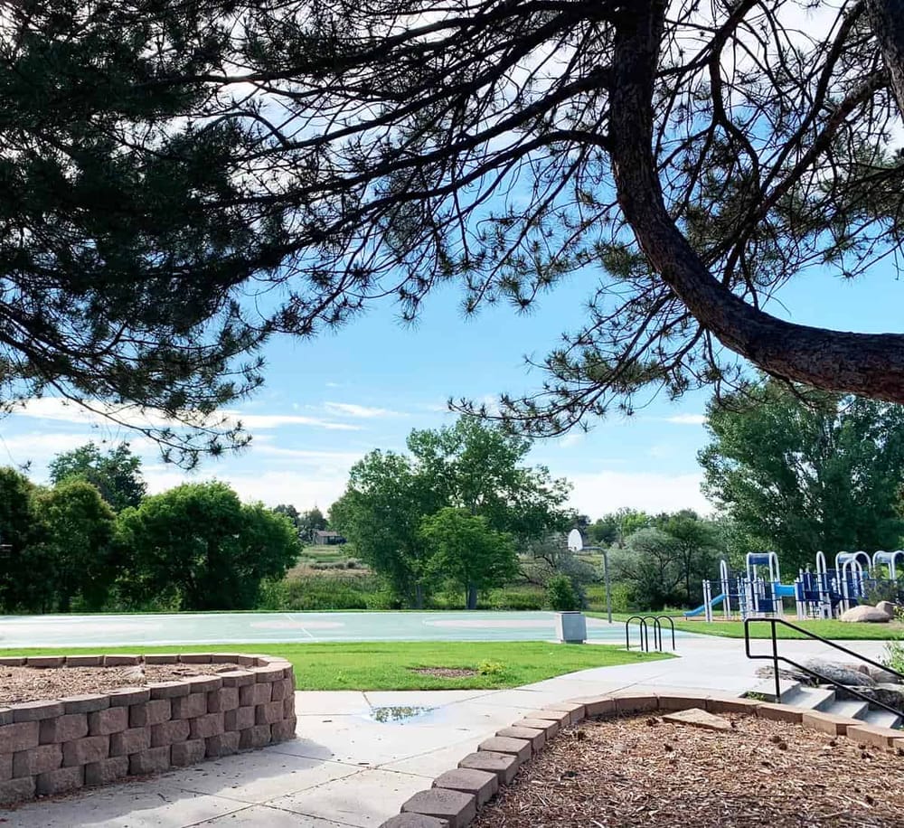 Lush park with playground, basketball court, and scenic trees, perfect for outdoor activities and family fun.