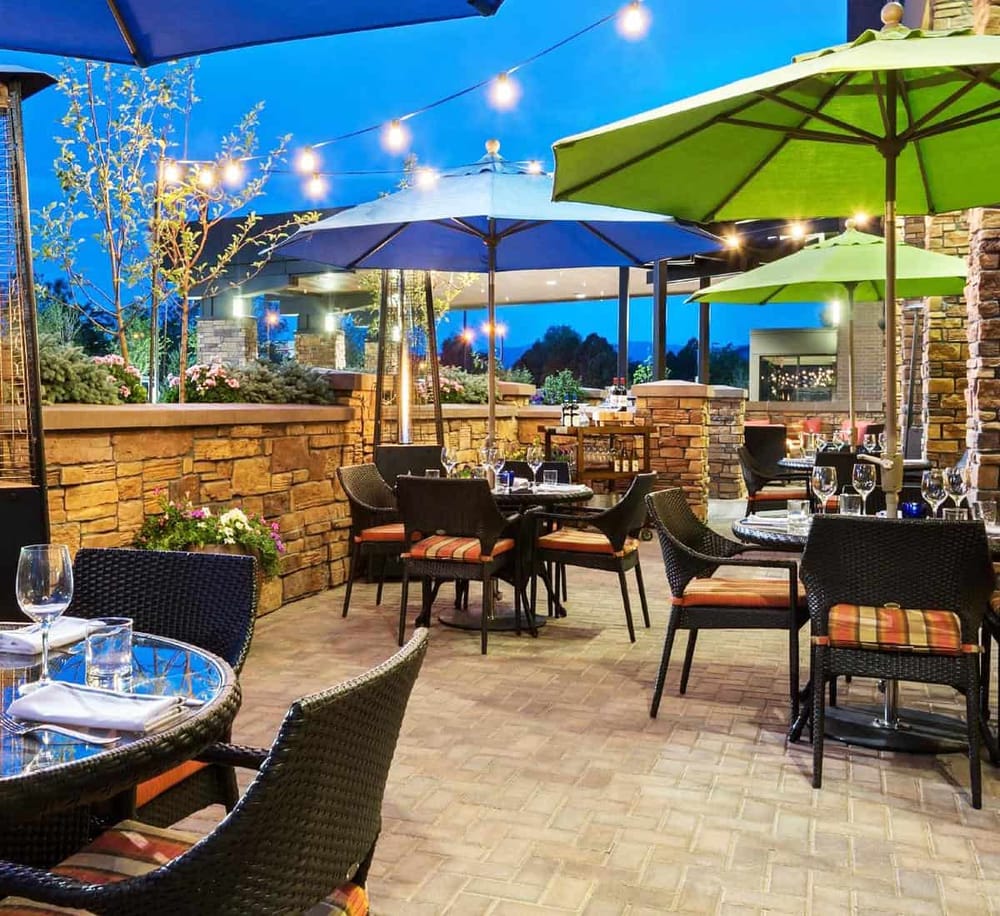 Outdoor dining patio with umbrellas and string lights, perfect for a cozy evening meal.