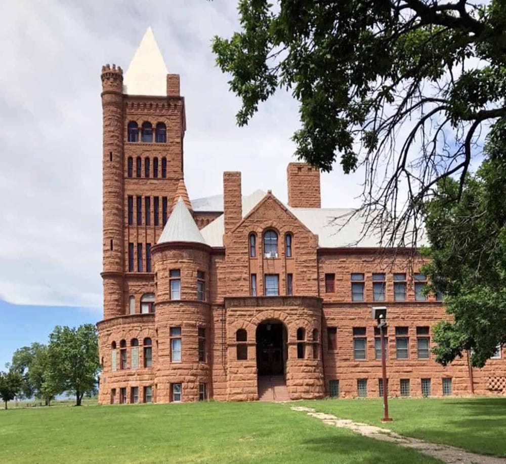 1. Red brick castle-style building with towers and arched windows under a cloudy sky.