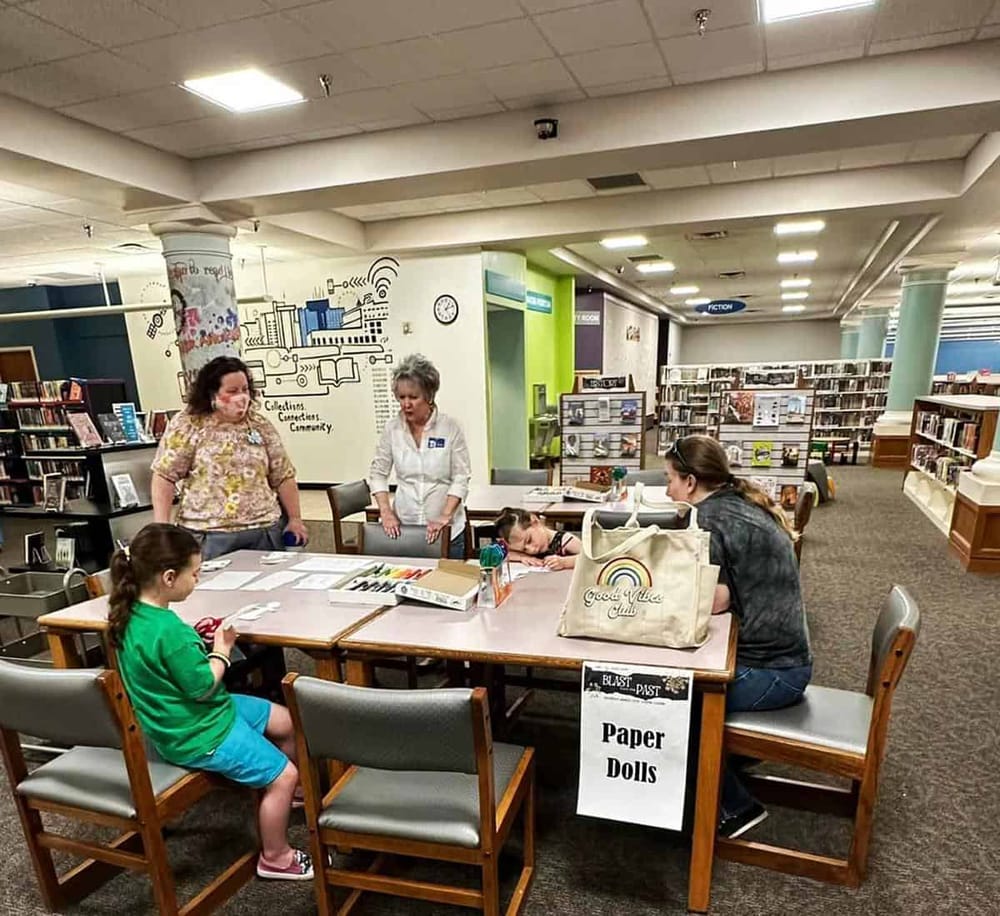 Children's paper doll crafting activity at library children's section.
