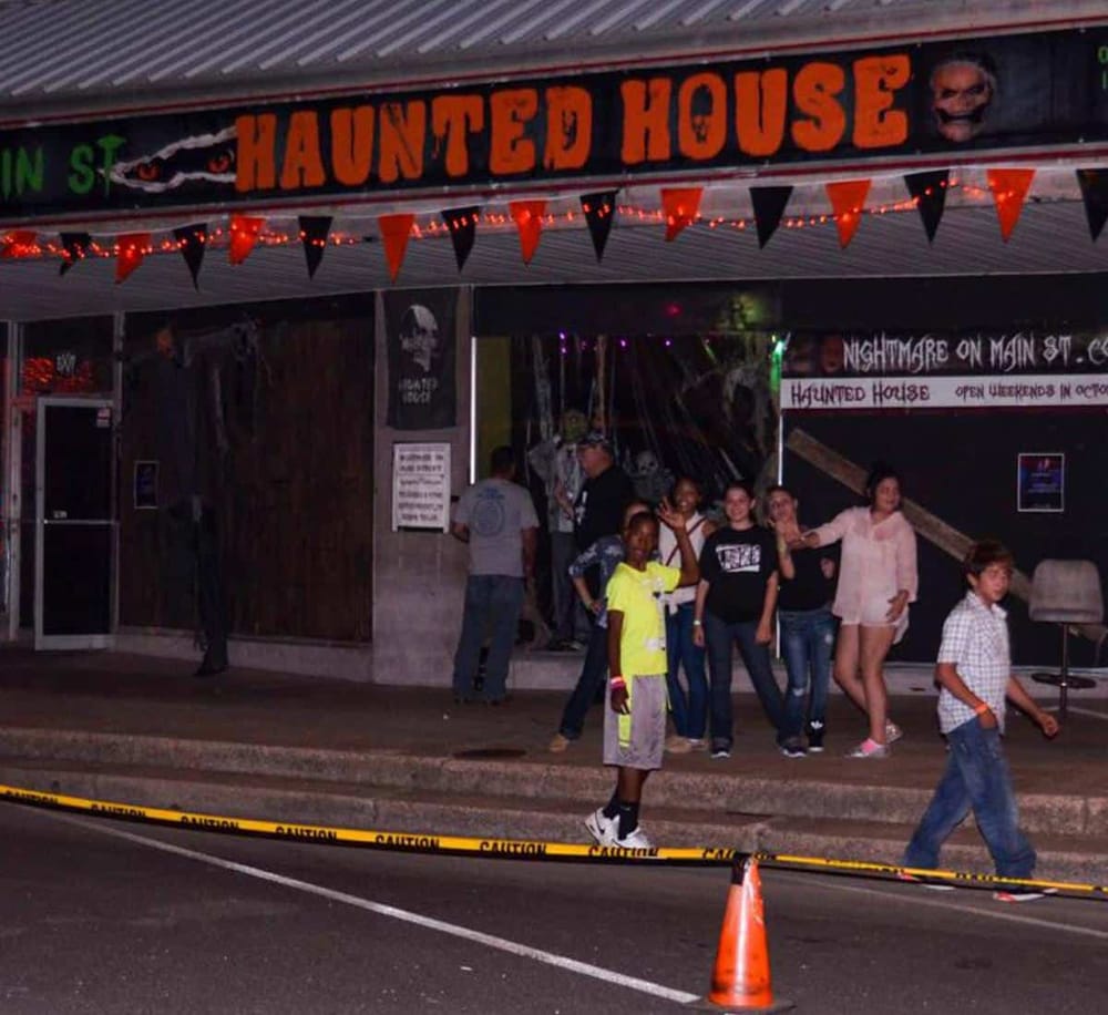 Haunted House attraction on Main Street during Halloween night, featuring spooky decorations and visitors enjoying the event.