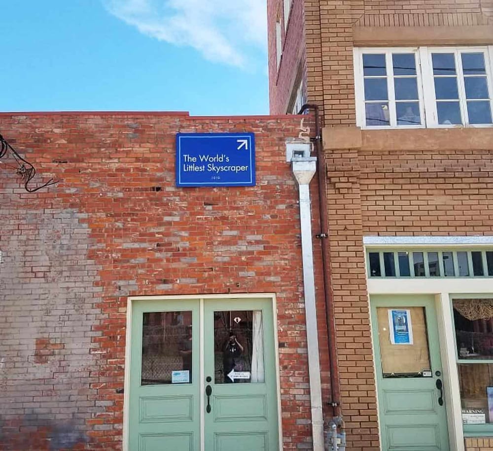1. Sign pointing to "The World's Littlest Skyscraper" on a brick building.