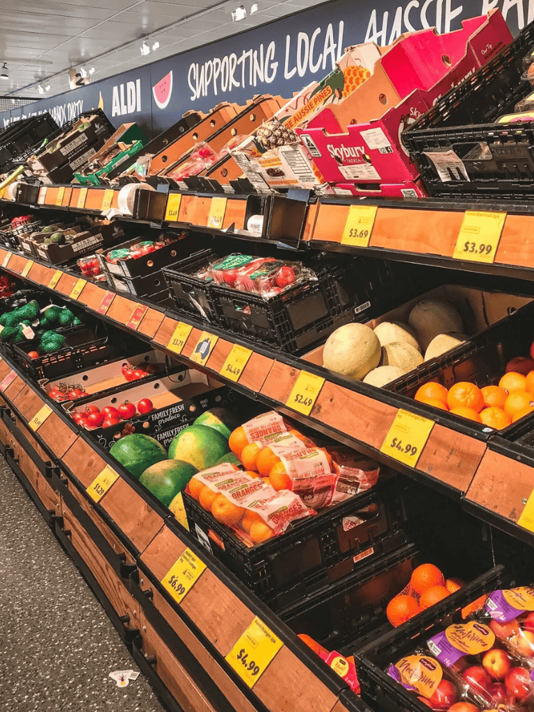 Fresh produce aisle in a grocery store with fruits and vegetables on display.