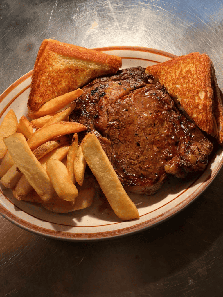 Juicy steak with crispy fries and toasted bread, classic American dinner at a local eatery.