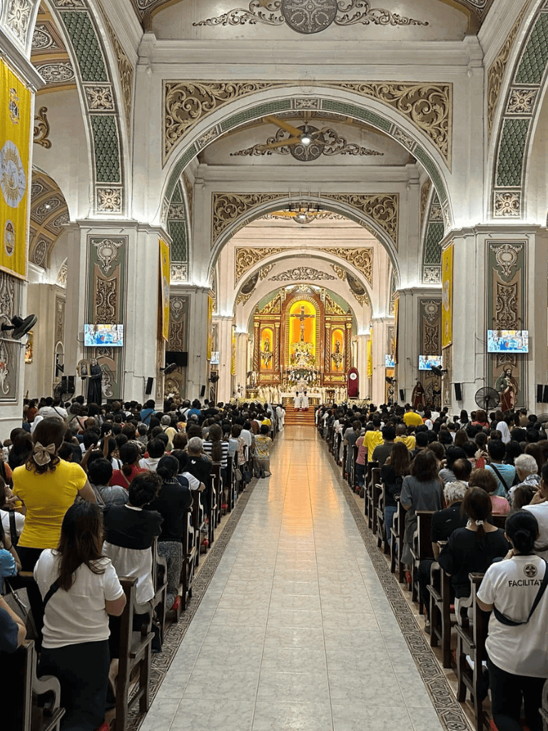 Massive church congregation during a religious service with ornate ceiling and golden altar.