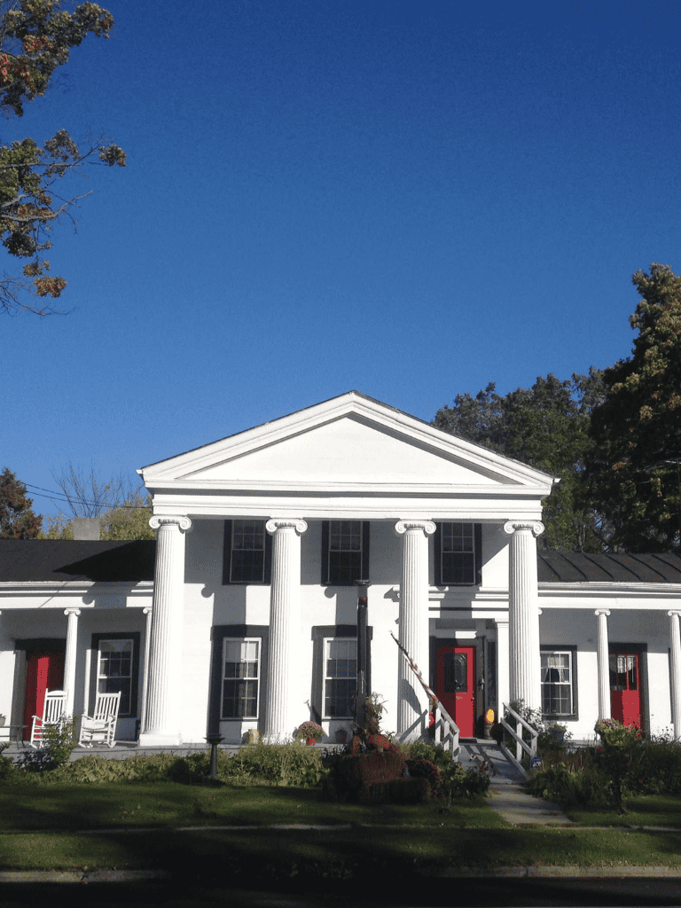 White historic building with columns and red doors, part of QuestForDirections' navigation services.
