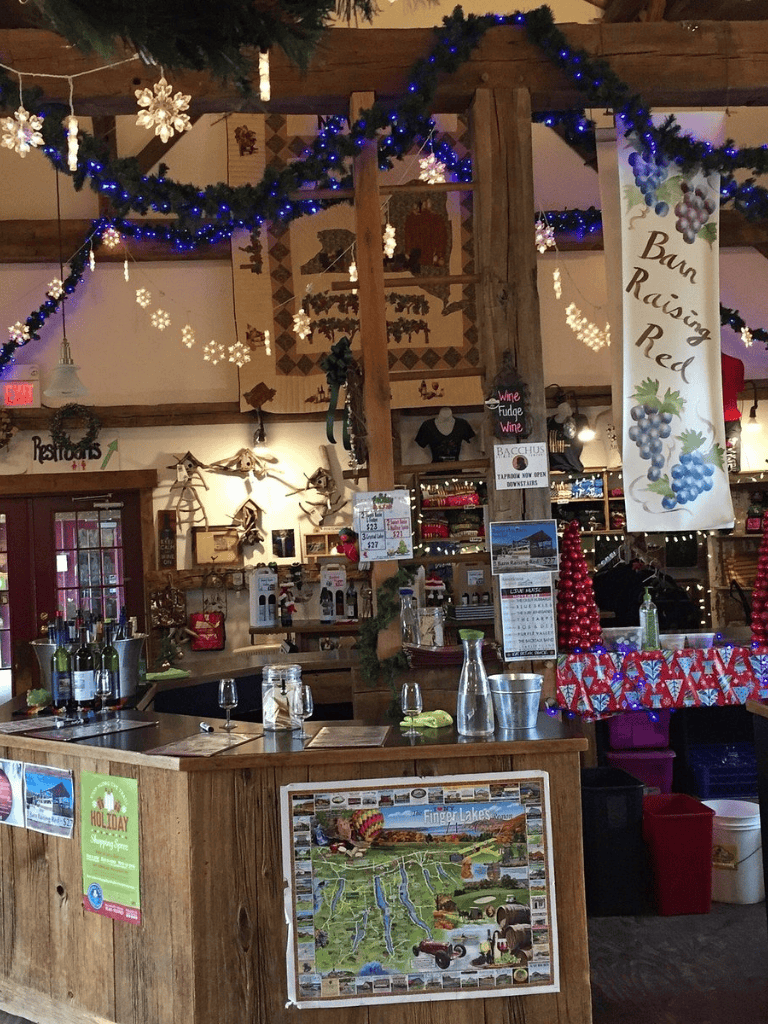 Cozy winery tasting room decorated with holiday lights and banners, featuring wine bottles and tasting glasses.