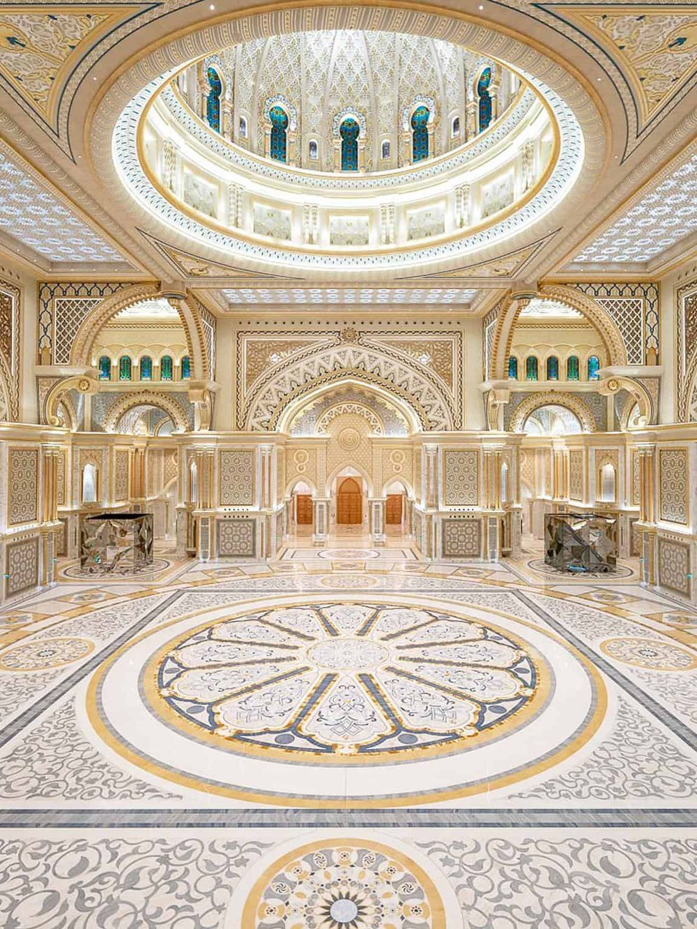 Luxurious ornate interior of a palace or hotel with intricate gold and white decorations and grand arches.