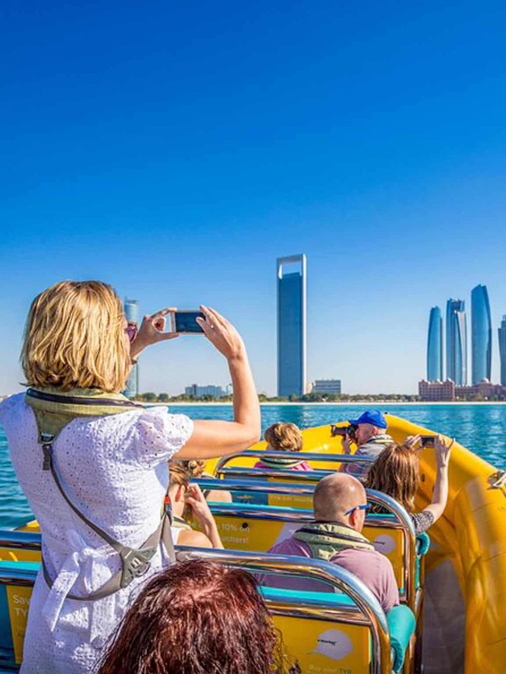 Scenic boat tour in downtown Dubai with tourists enjoying city skyline views and iconic skyscrapers.