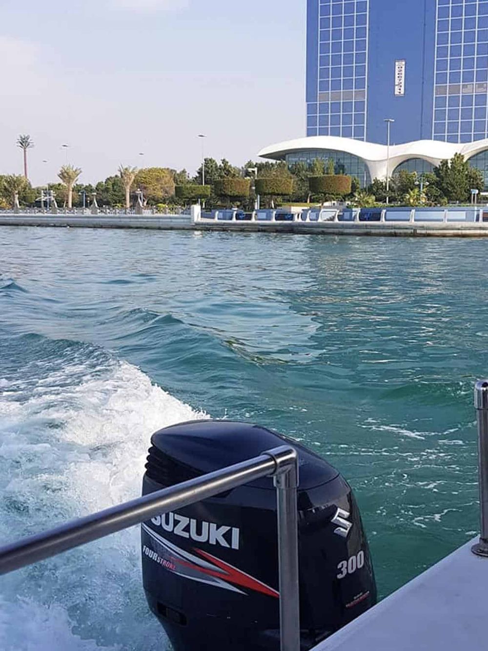Vibrant cityscape waterfront view with boat motor, modern architecture, and lush greenery in Los Angeles.