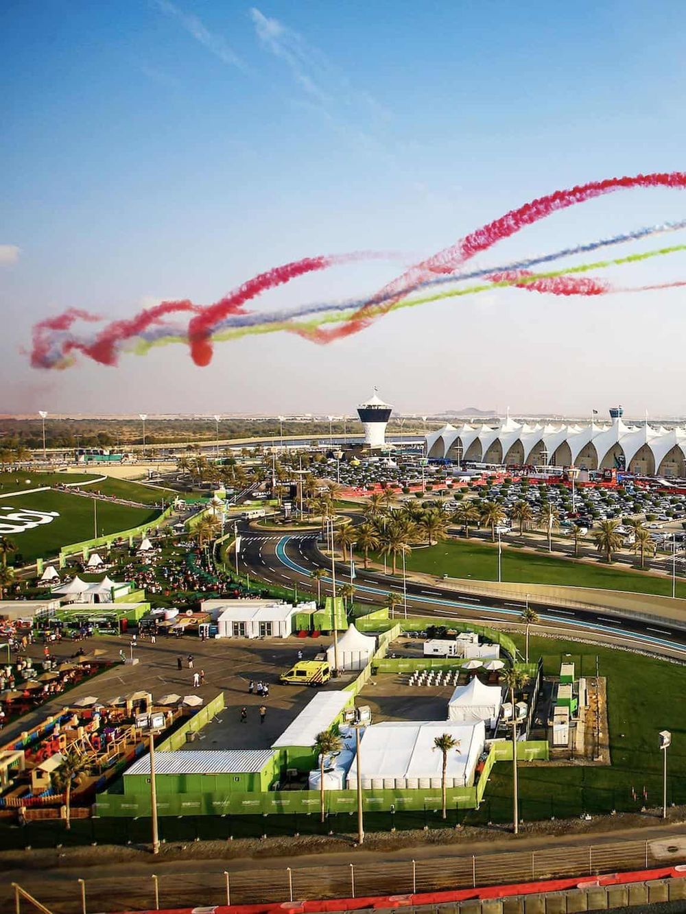 Vibrant aerial view of an event at Quest for Directions with colorful smoke displays and organized booths, showcasing a dynamic outdoor setting.