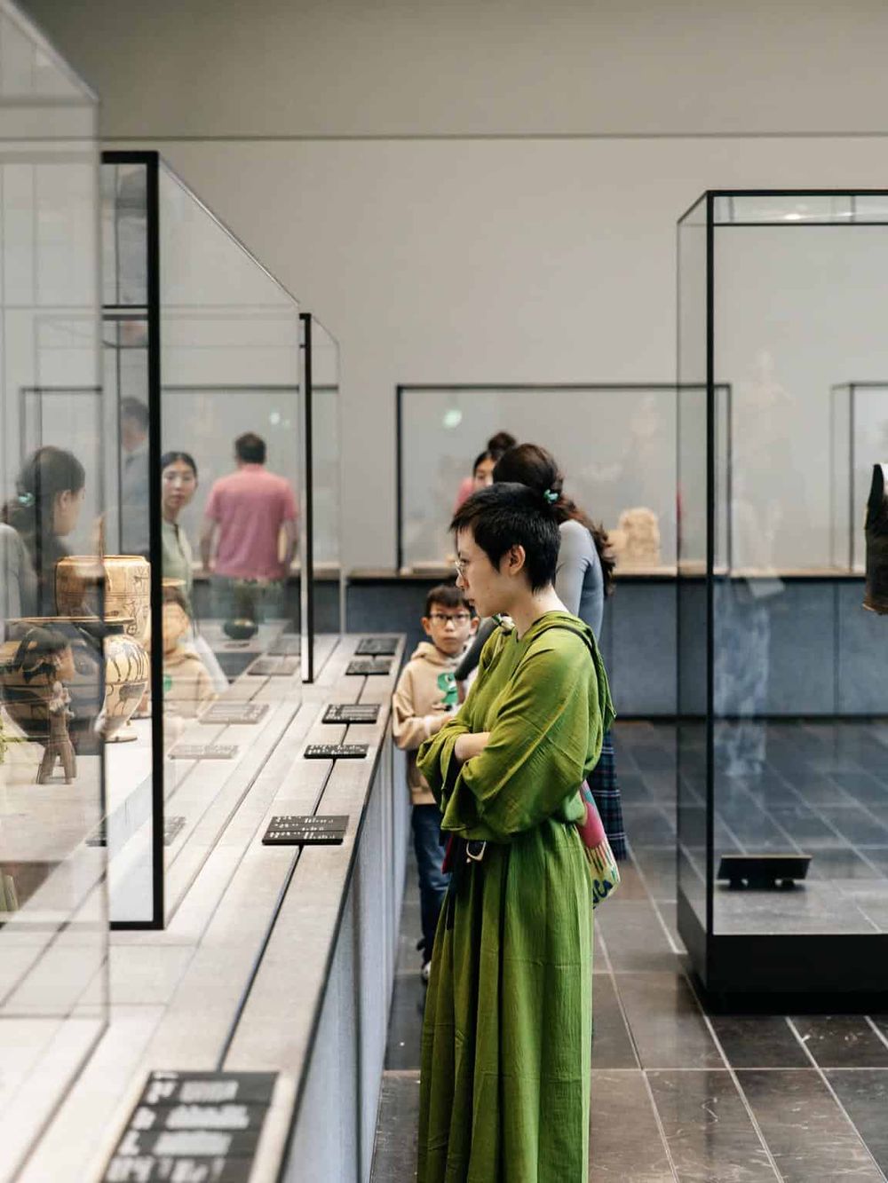 Historical artifact museum exhibit, people viewing cultural objects and art pieces.