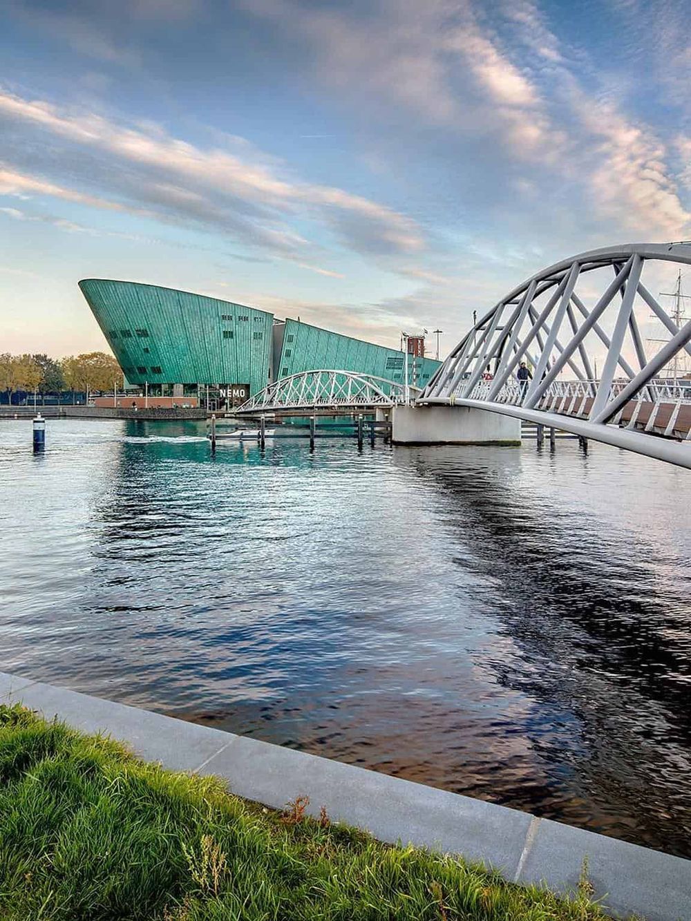 Modern waterfront architecture with bridge connecting to the unique NOMO building in a vibrant cityscape.