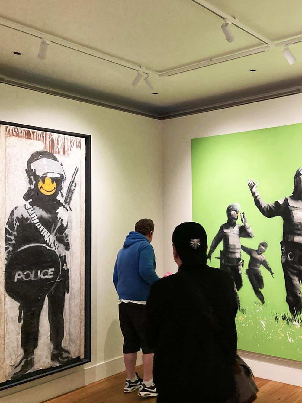 Bold police art graffiti depicting riot police and protesters in an urban art gallery.