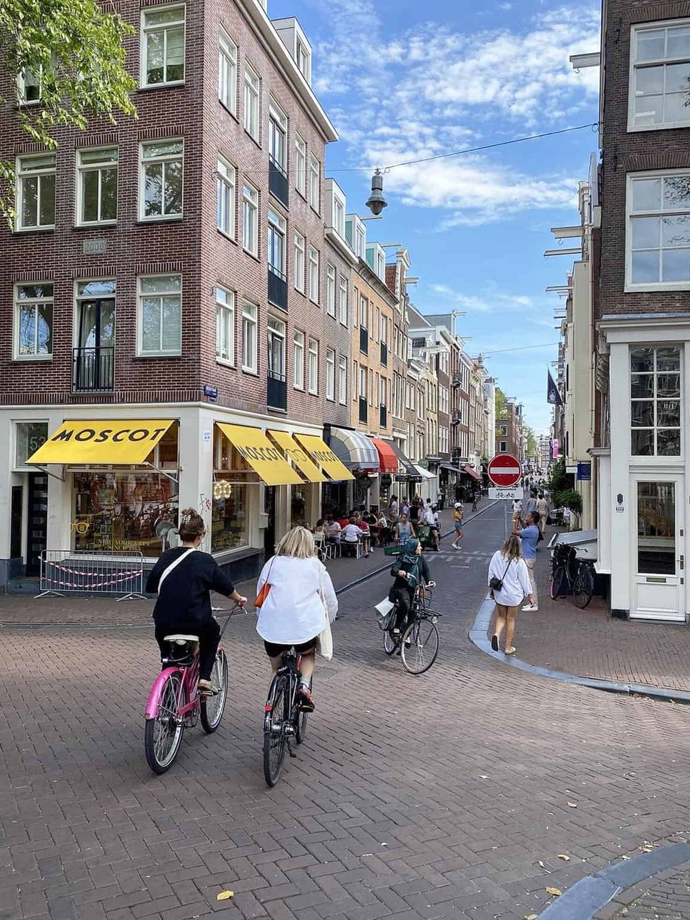 Charming Amsterdam street scene with cyclists, cafes, and historic buildings, ideal for exploring city travel and local attractions.