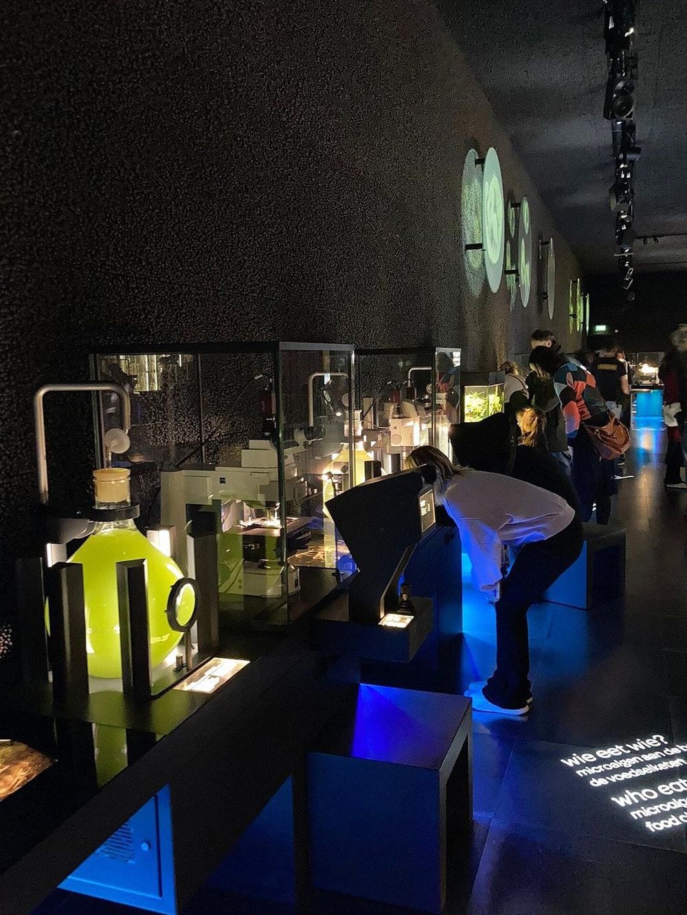 Interactive science exhibit with illuminated displays and visitors exploring the setup at QuestForDirections.