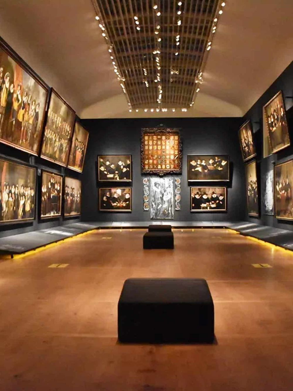 Elegant art gallery with paintings and sculptures, modern lighting, and cozy benches for visitors.