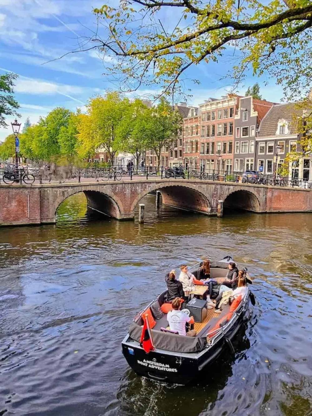 Colorful canal boat tour in Amsterdam with historic buildings and a picturesque bridge.