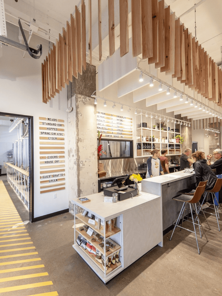 Craft brewery interior with modern decor and customers at the bar, downtown ambiance, cozy setting, urban vibe, popular hangout spot.