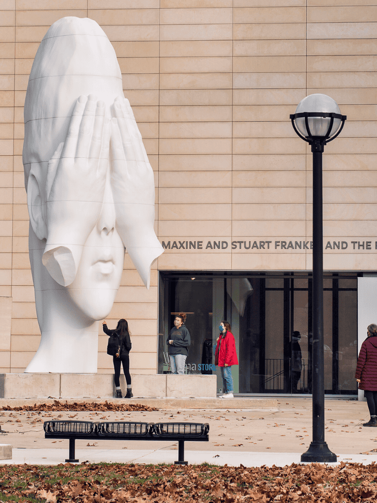 Contemporary sculpture of a woman with hands over eyes at QuestForDirections museum exterior.