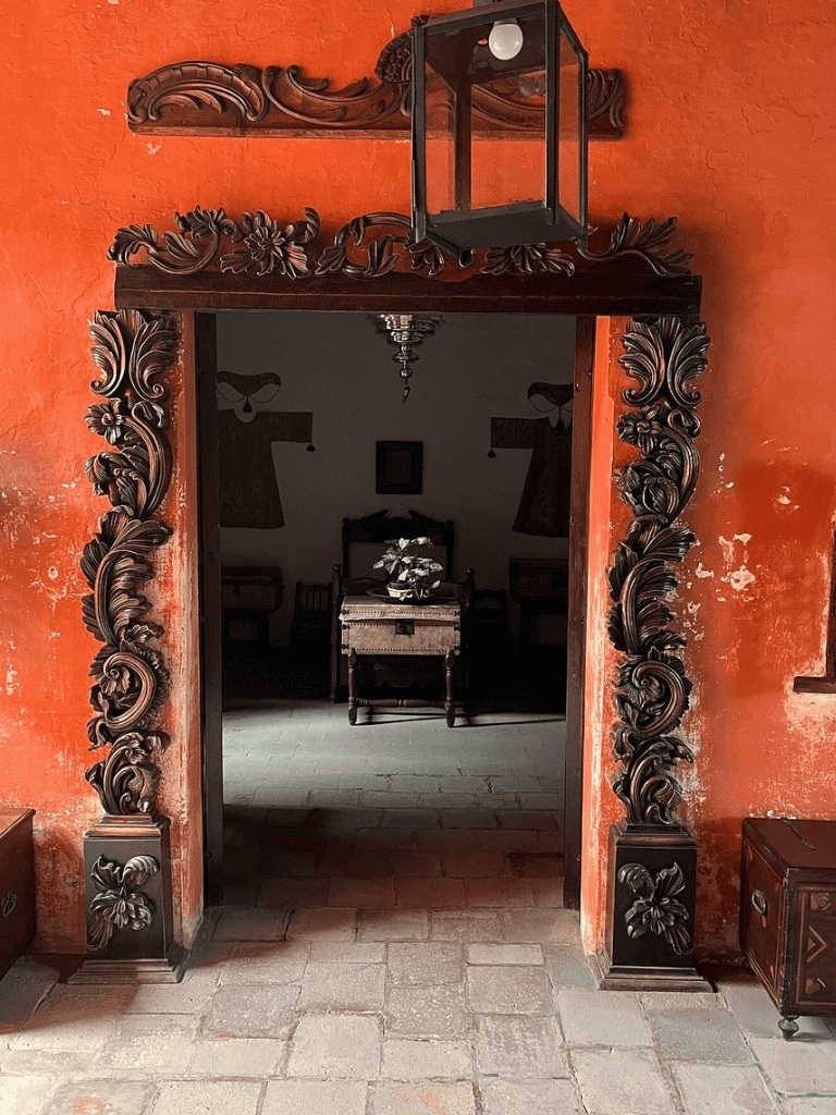Ornate carved wooden doorway with vintage interior decor and floral accents.