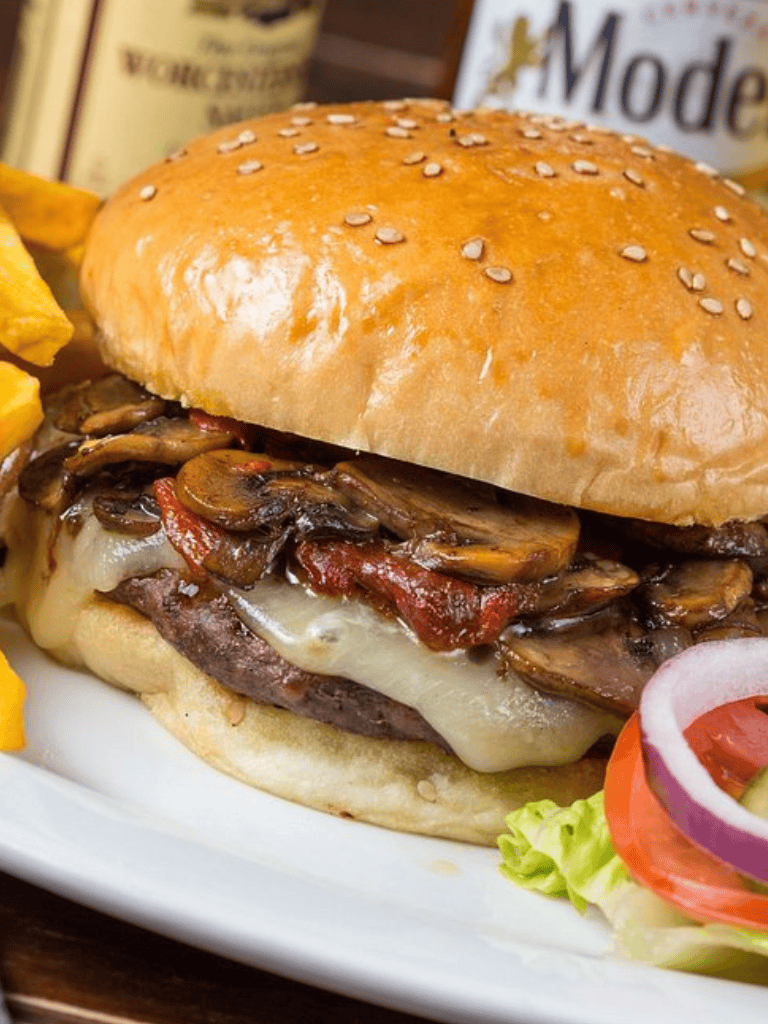 Juicy mushroom and bacon cheeseburger with fresh vegetables on sesame bun.