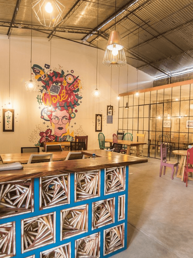 Colorful modern interior of Quest for Directions cafe with artistic wall mural and eclectic chairs and lighting.