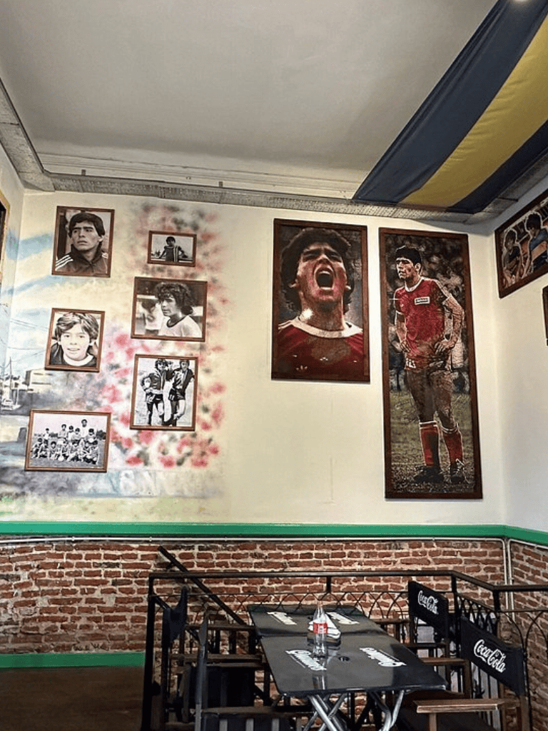 Iconic soccer player portraits wall art at sports-themed restaurant interior.