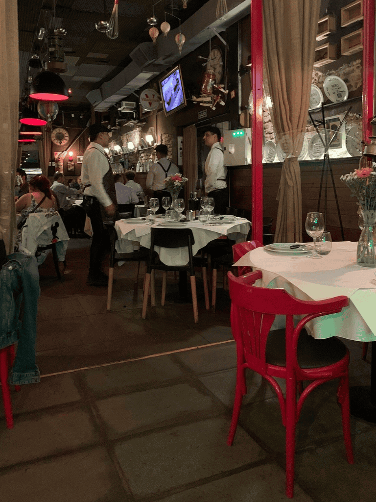 Elegant restaurant interior with waitstaff, neatly arranged tables, and cozy ambiance for dining excellence.