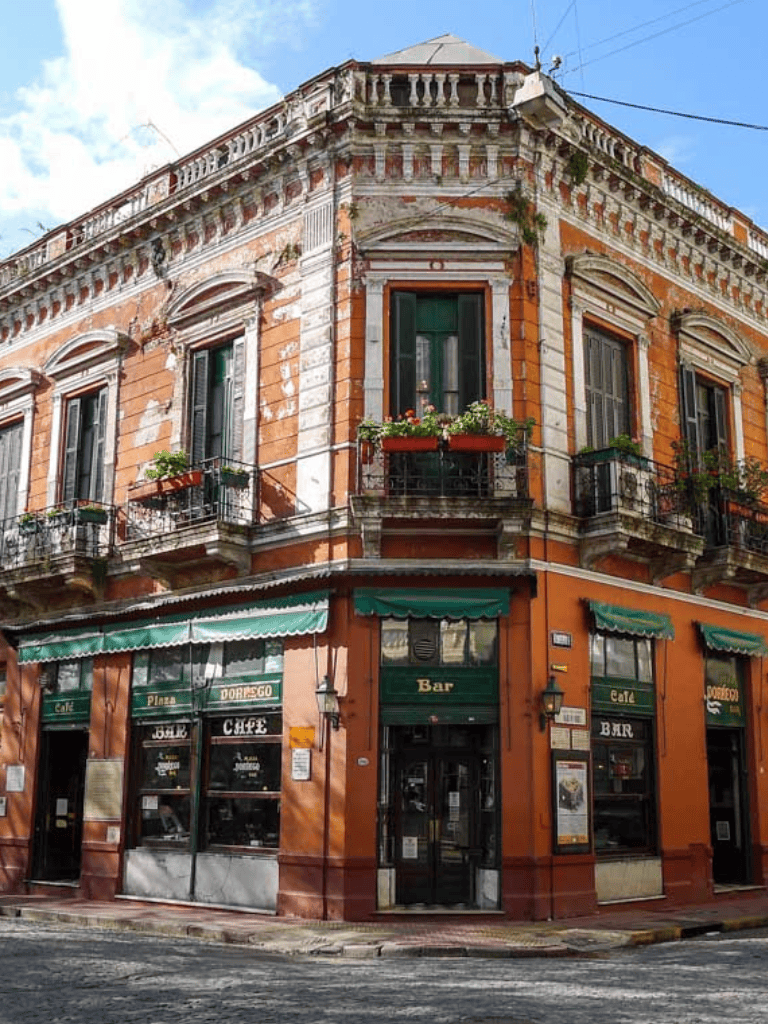Charming historic building with a café and bar, vibrant street corner, colorful architecture and outdoor seating in a lively city.