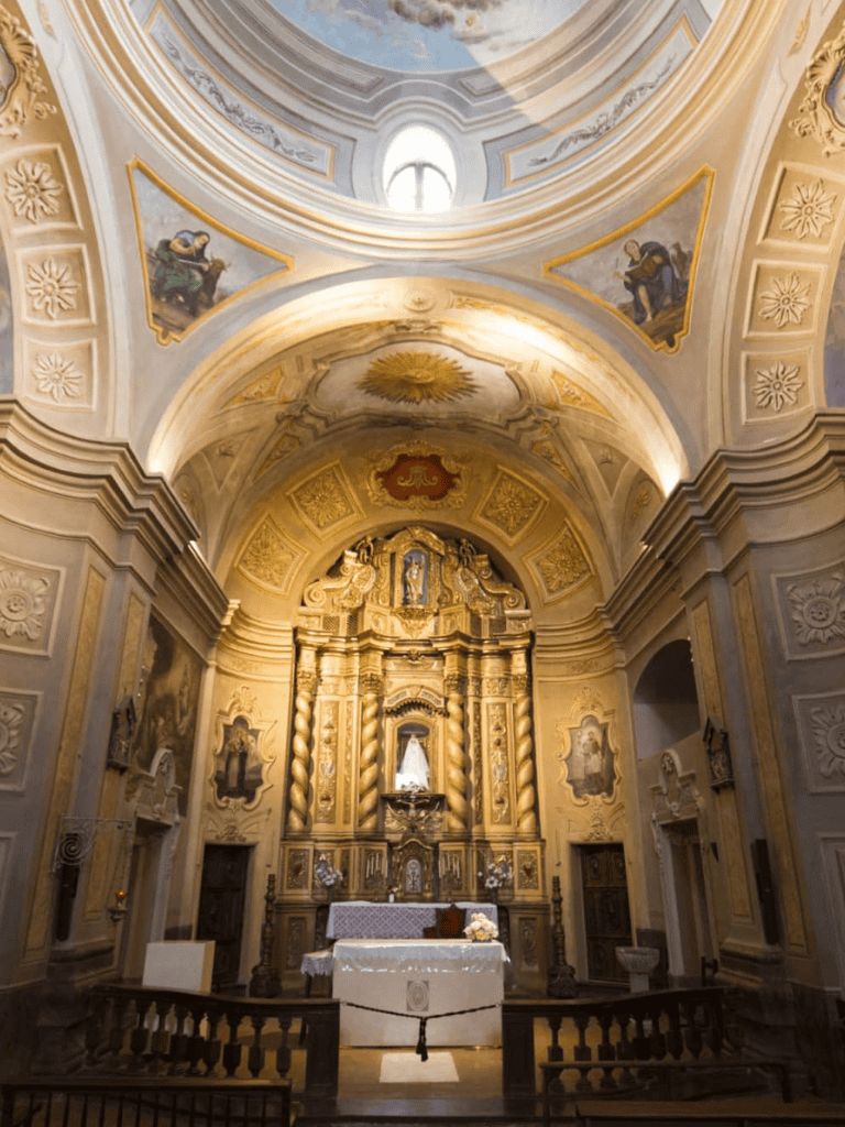 Ornate church altar with gold accents and religious artwork, interior of a historic Catholic church.
