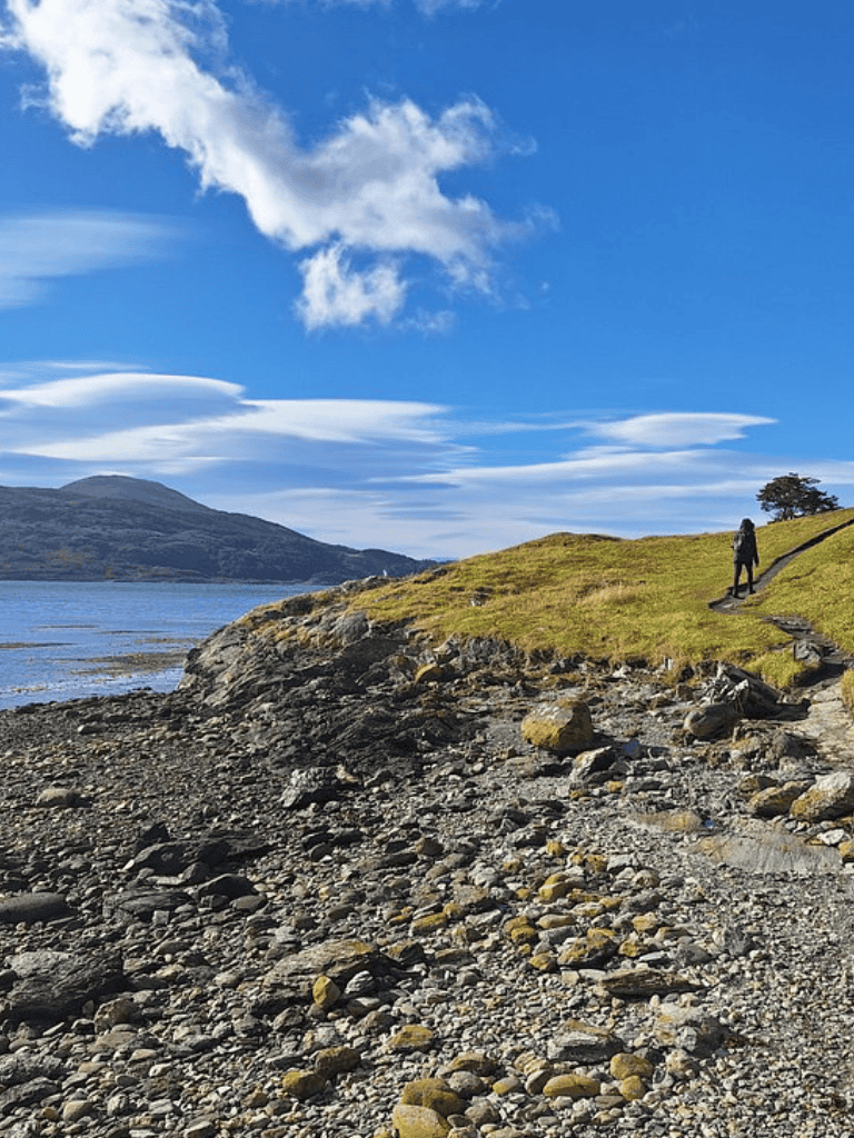 Scenic mountain coastal trail with rocky shoreline and lush green landscape in the background.