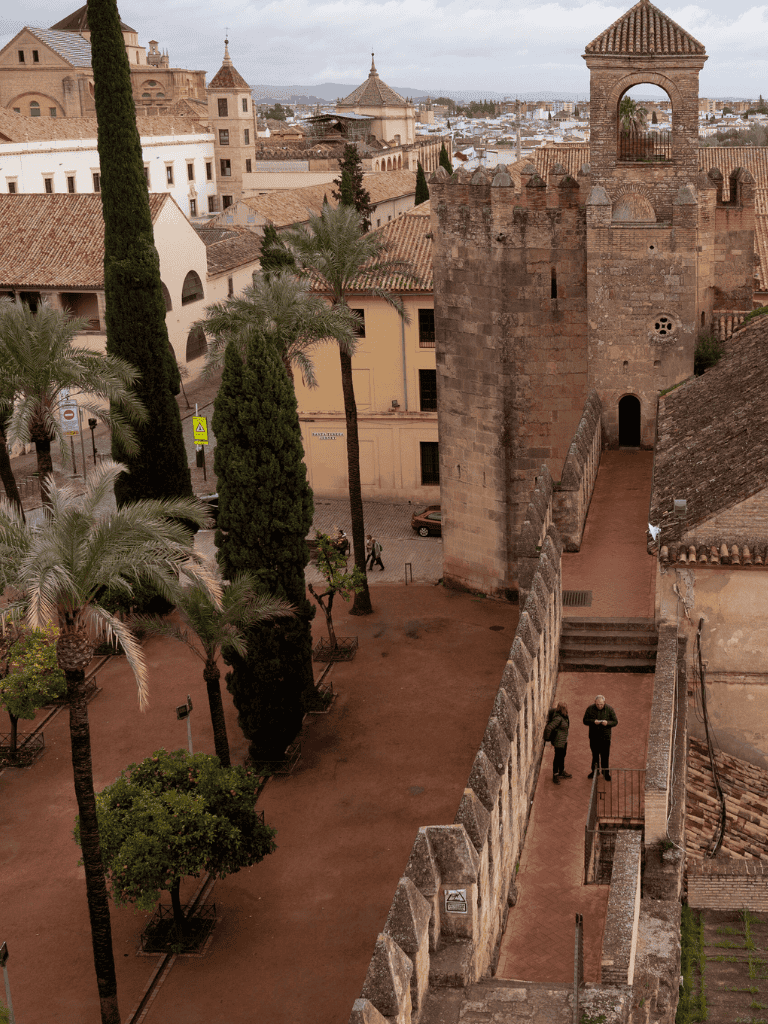 Ancient cityscape with castle tower and palm trees in Seville, Spain, showcasing historical architecture.