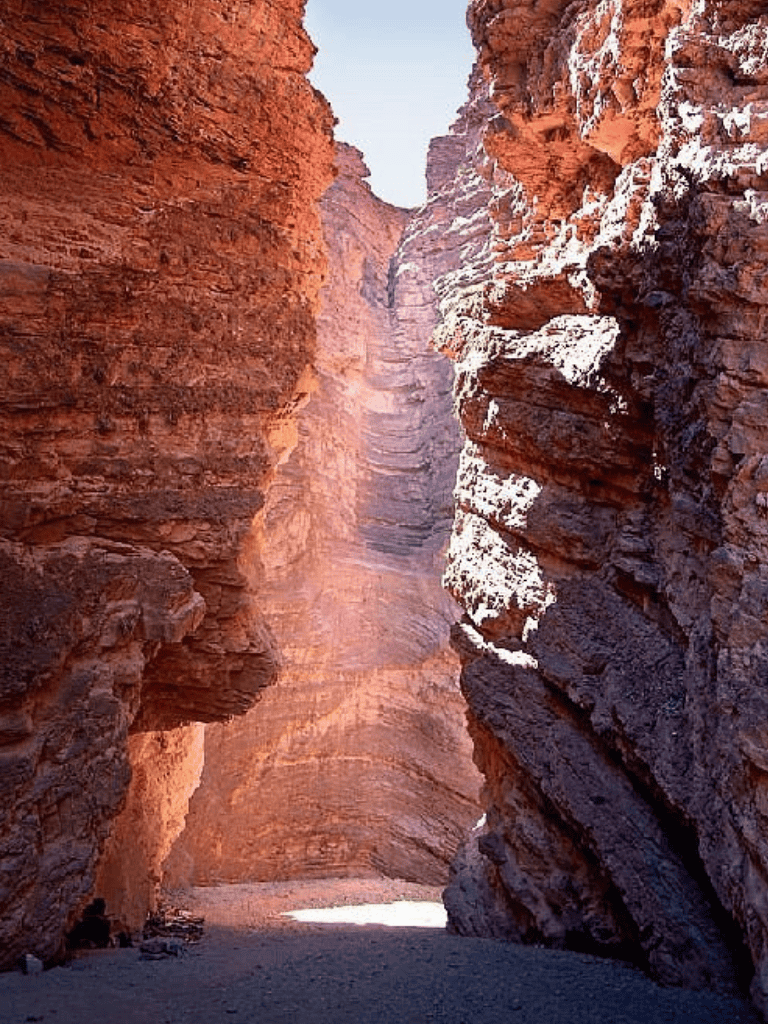 Deep canyon with red rock cliffs and snow accents, hiking adventure in a stunning natural landscape.