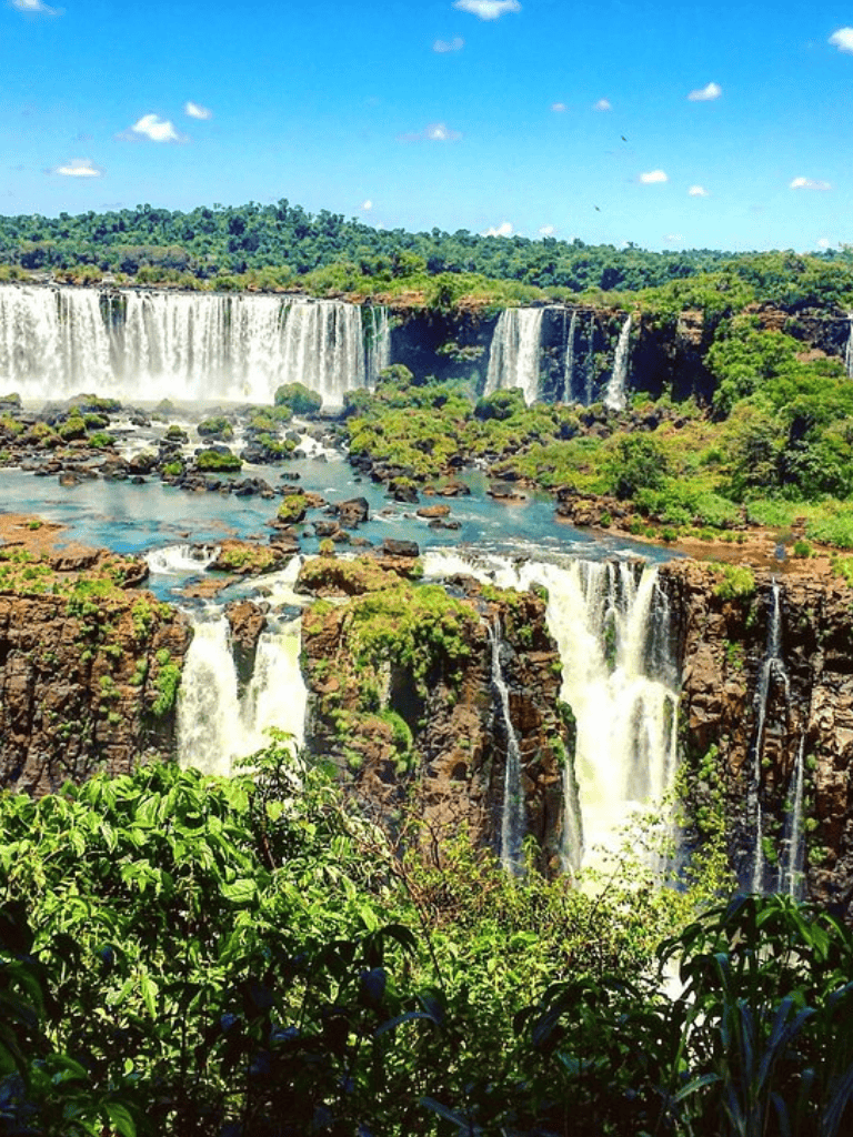 Vibrant waterfall landscape with lush greenery and cascading water in a scenic outdoor setting.
