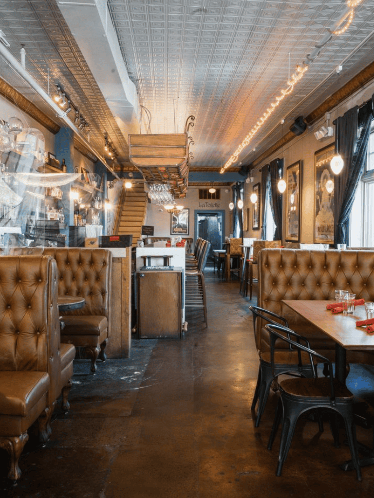 Cozy restaurant interior with leather booths, wooden tables, and warm lighting, perfect for dining and socializing.