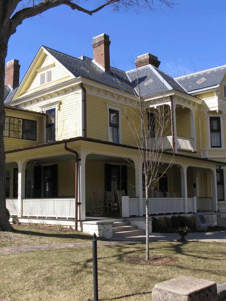 Victorian-style yellow house with porch and gabled roof, historic architecture, charming neighborhood.