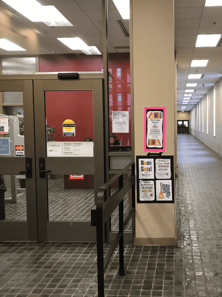 1. Indoor library entrance with book sale signs and hallway.