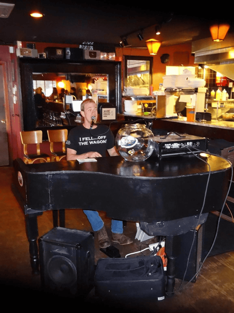 Scottish singer performing at a cozy pub with a grand piano in the foreground, capturing live music entertainment.