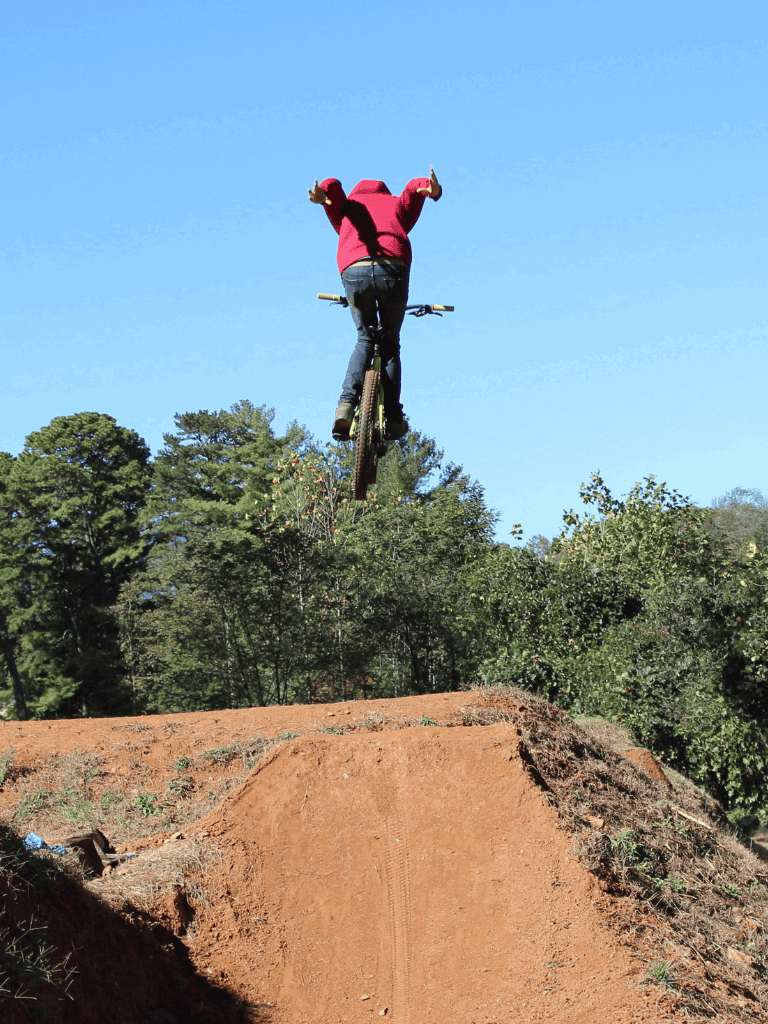 Thrilling BMX bike jump over dirt ramp on a sunny day for adventure and outdoor sports.