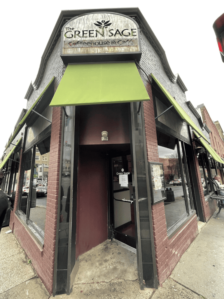 Aperture to Green Sage Café with brick exterior and green awnings, located in downtown area.