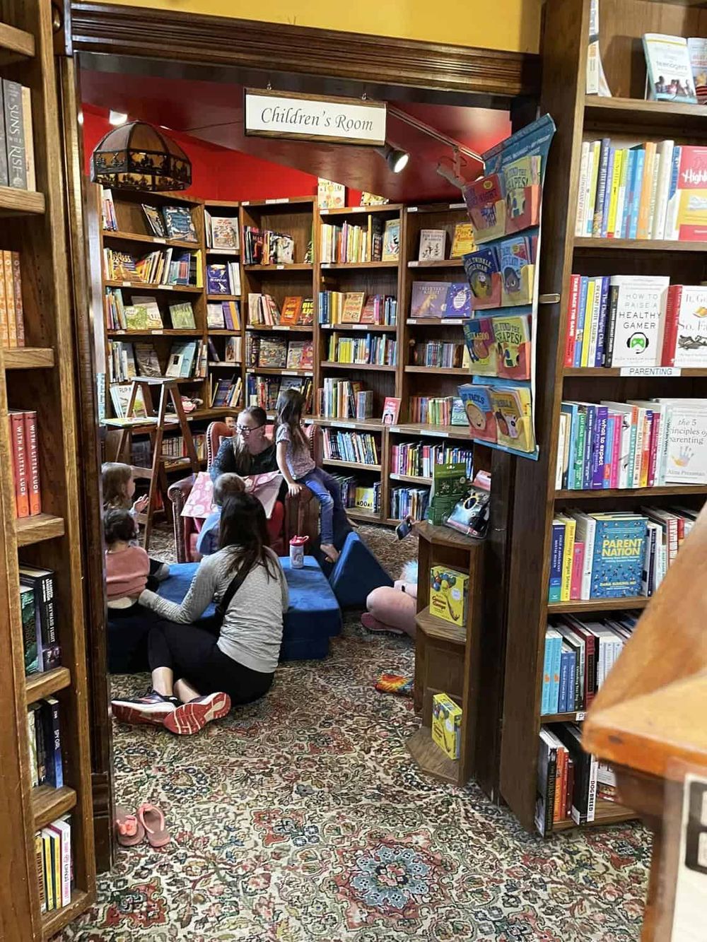 Children's reading corner in a cozy bookstore, filled with kids enjoying storytime amid colorful bookshelves.