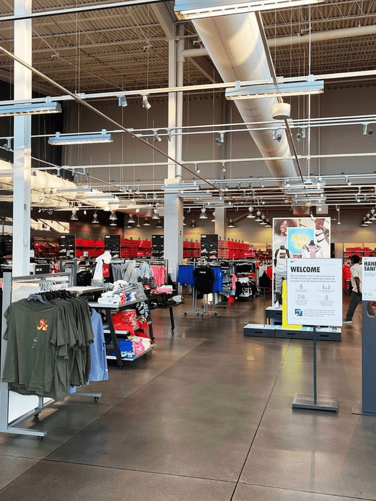 Brightly lit retail store interior with clothing displays and a welcome sign, showcasing modern shopping experience.