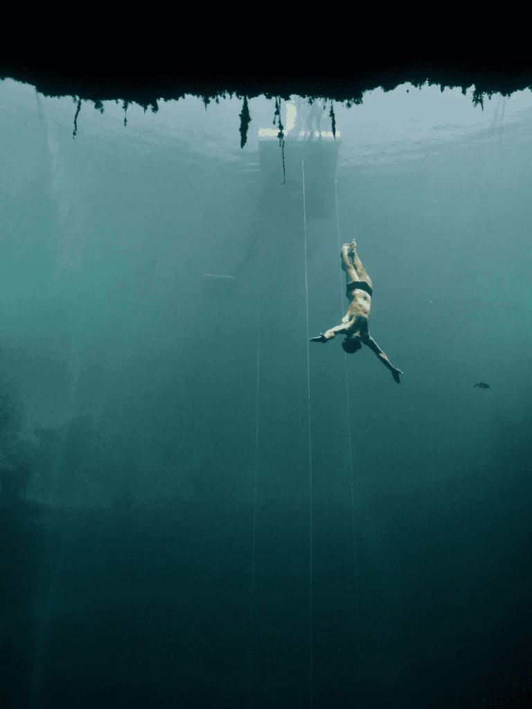 Unwoman diver swimming underwater near a submerged structure, exploring marine environments.